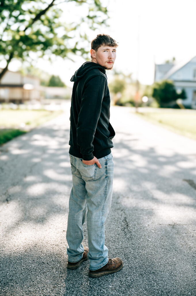 Senior boy in Carhartt hoodie posing during a rustic outdoor senior session